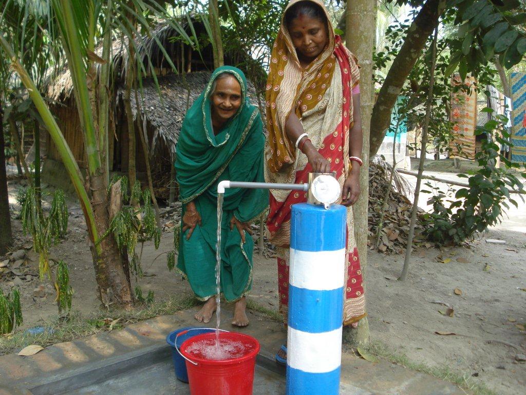 Women fill their buckets with water from an outlet connected to an overhead tank